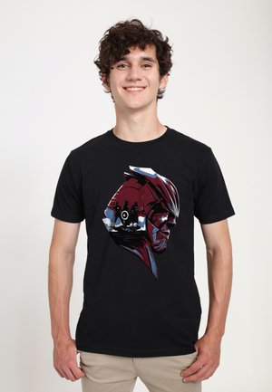 Sort bomulds T-shirt med et grafisk design af et hjelmede ansigt i rød og hvid, med tegn og elementer i baggrunden.