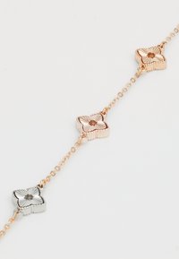 Rose-guld og sølv kædearmbånd med tre skiftevis blomsterformede led, tekstureret med rillet kanter og et centralt motiv.