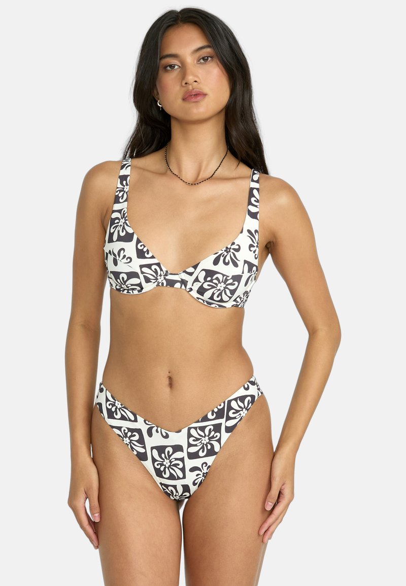 Bikini in bianco e nero con motivo, caratterizzato da una scollatura profonda e spalline larghe sulla parte superiore, completato da un fondo a taglio alto con copertura minima.