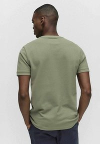 Olivgrön kortärmad t-shirt med rund halsringning och en slät, åtsittande textur, med en rak fåll och subtila sömnadsdetaljer.