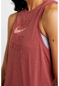 Top sin mangas de Nike en color burdeos con escote redondo y texto impreso "AMOR, SOLO HAZLO". Hecho de una tela suave con un corte relajado.
