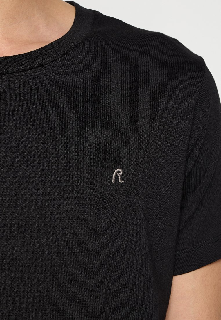T-shirt noir à manches courtes en coton lisse, avec un petit logo gris brodé sur le côté gauche de la poitrine.