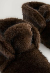 Braune Kunstfellslipper mit einer weichen, flauschigen Textur. Abgerundete Oberseite und offenes Rückdesign, ausgestattet mit dickem Fell am Kragen.