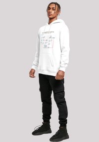 Hvit hettegenser med et trykt flytskjema-design i blått og rødt. Kombinert med svarte cargobukser og svarte høye sneakers.
