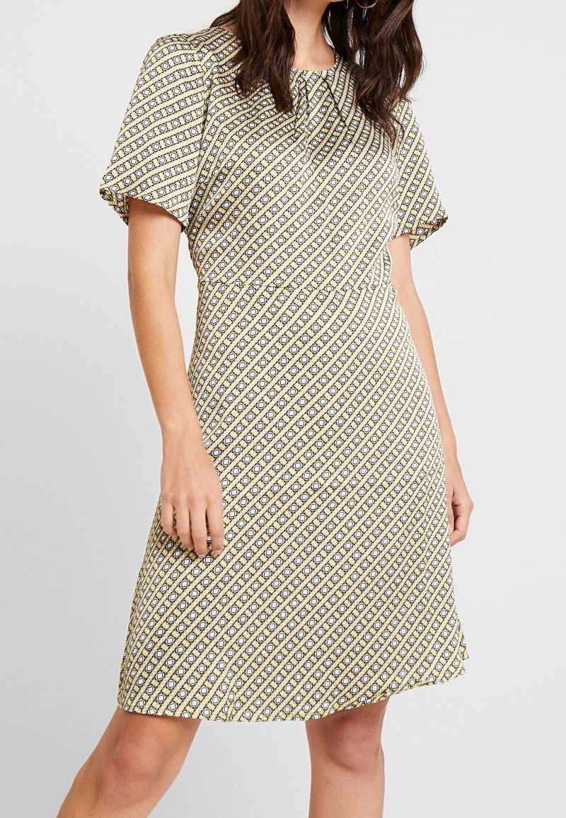 Kurzärmeliges Kleid mit einem gelb-blauen Rautenmuster, gerafftem Ausschnitt, fließendem Stoff und knielanger Länge.