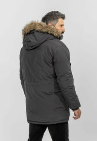 Mørkegrå isoleret parka med en pelsforet hætte, der har en lynlås foran, elastiske manchetter og en mellemlang længde. Glat tekstur.