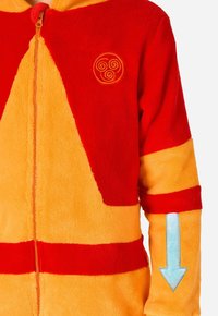 Punane ja kollane fliisist ühekordne kombinesoon esiluku, rinnal asuva ringikujulise embleemi ja paremal varrukal sinise noole aktsendiga.