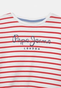 Biała koszulka w czerwone poziome paski. Niebieski przyszyty logo "Pepe Jeans London" z przodu. Okrągły dekolt, miękka faktura.