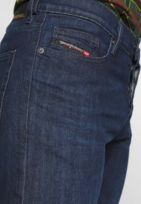 Mörkblå denimjeans med slim fit, klassisk femficksdesign och en liten röd och svart logotyp på bakfickan.