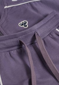 Lila bomullssweatpants har en texturerad midja med dragsko, vita sidodetaljer och en liten broderad logotyp.