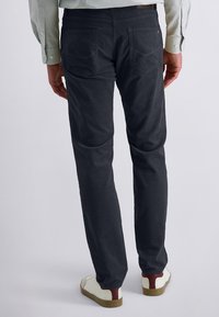 Dark gray chinos with a straight fit. Features back pockets, soft texture, and a slightly tapered leg. Paired with white sneakers.