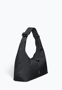 Borsa a spalla nera in nylon con forma curvata, dotata di una parte superiore con zip e tracolla regolabile. Logo visibile sul davanti. Texture liscia.