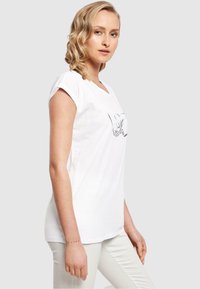 Hvid bomulds T-shirt med opslåede ærmer, der har et sort grafisk design af hænder, der danner et hjerte på forsiden. Glat tekstur, afslappet pasform.