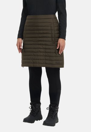 Person wearing an olive green quilted knee-length skirt, black leggings, black hiking boots, and a long-sleeve black top.