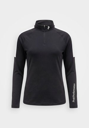 Sort atletisk top med lange ærmer med hvide skulderstriber, kvart lynlås og "PeakPerformance" tekst på højre ærme mod en ensfarvet baggrund.
