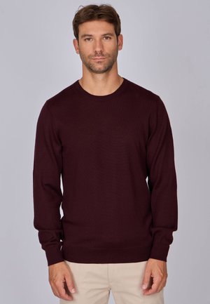 Pull en maille bordeaux avec un col rond, des manches longues et des poignets et un ourlet côtelés. Texture douce, design simple sans motifs ni embellissements.