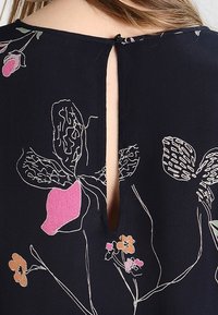 Granatowy top w kwiatowy wzór; posiada odkryte plecy z rozcięciem i zapięciem na guzik; miękka tkanina i delikatne detale szwu.