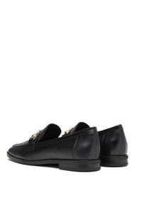 Zwarte leren loafers met een gladde textuur, voorzien van goudkleurige hardware aan de voorkant. Rond de neus en een lage gestapelde hak.