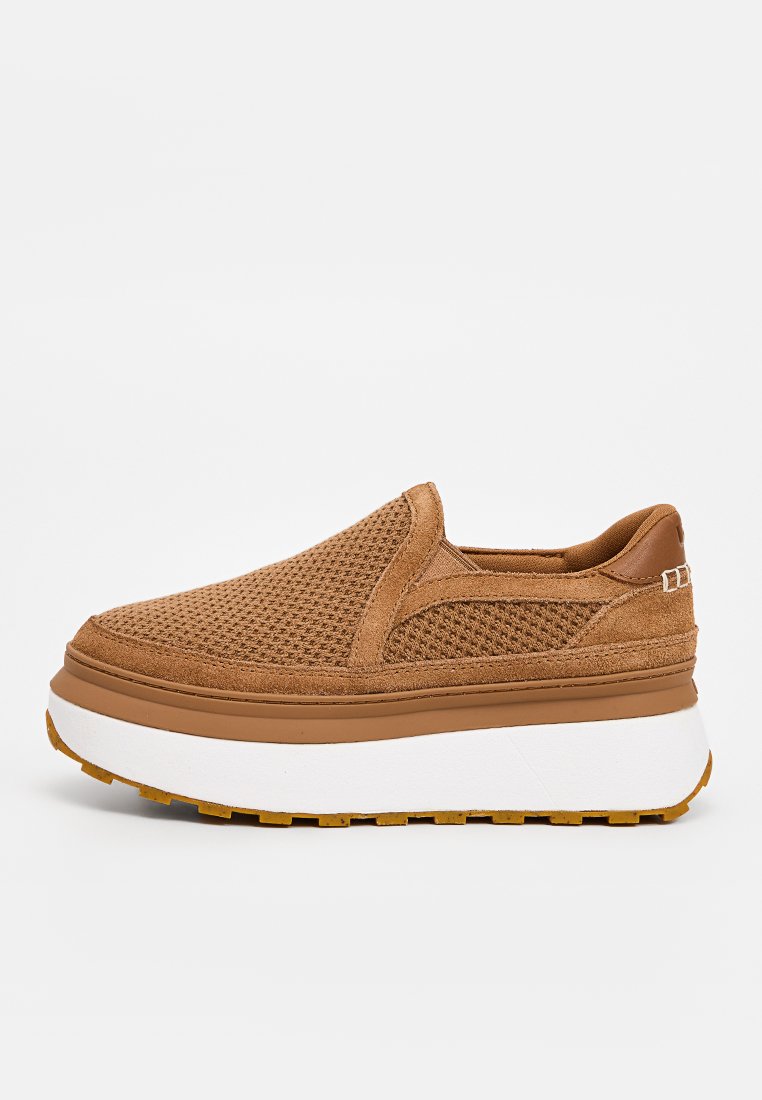 Chaussures brunes à enfiler avec une tige en tissu texturé, des détails en maille et une semelle intermédiaire blanche épaisse. La semelle extérieure présente un motif en alvéoles.