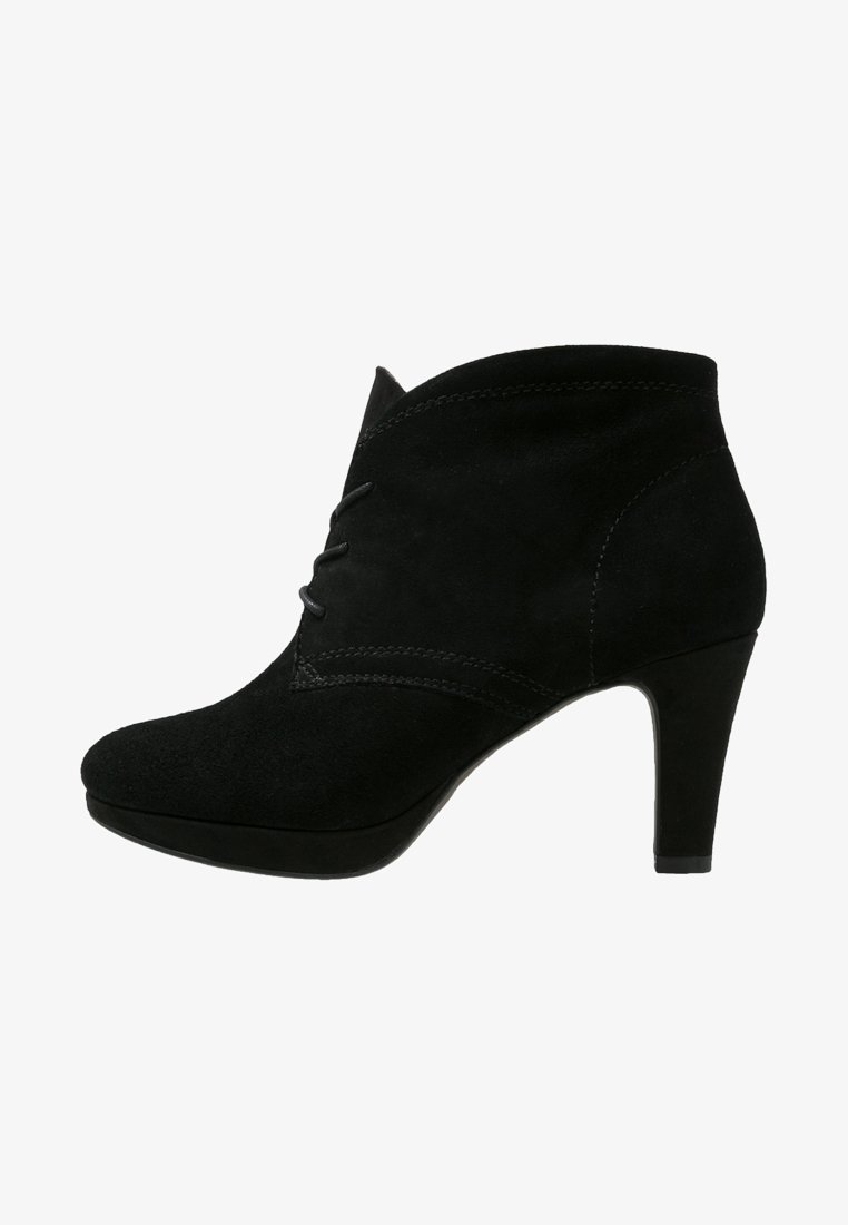 Botas de ante negras hasta el tobillo con punta afilada, línea superior curva y un tacón de 10 cm. Presentan costuras decorativas en la parte delantera.