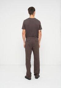 Brun bomulds t-shirt med rund hals og korte ærmer, parret med brune bukser med baglommer og en afslappet pasform.