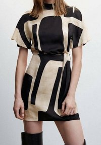Šaty s abstraktním vzorem v černé a béžové barvě vyrobené z hladké látky, mají krátké rukávy, vysoký límec a pásek v pase pro přiléhavý siluetu.