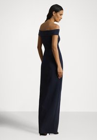 Ναυτικό μπλε φόρεμα ελεύθερο στους ώμους με εφαρμοστή γραμμή στο μπούστο και μακρύ φόρεμα μέχρι το πάτωμα, με λεία υφή και κομψές γραμμές.