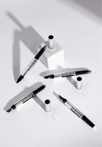 Vijf wenkbrauwpennen in verschillende tinten liggen op een witte ondergrond. Elk heeft een zwart en zilver ontwerp, met borstelpunten en terugtrekbare mechanismen.