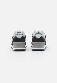 Black and gray New Balance sneakers with a suede and mesh upper, featuring a light blue heel, white midsole, and black rubber outsole.