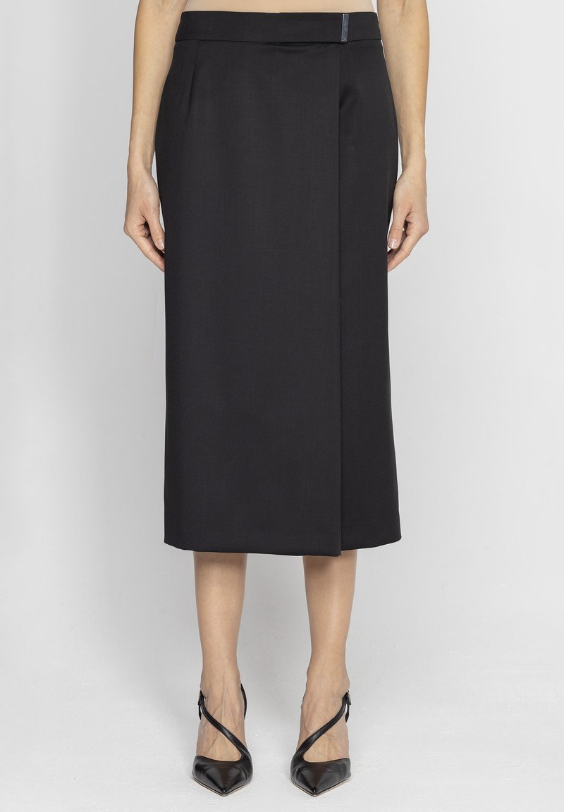 Czarna spódnica ołówkowa z pasem i zaszewką z przodu. Tkanina ma gładką fakturę, długość do kolan. Noszona z czarnymi szpilkami.