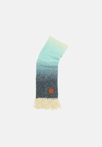Écharpe tricotée avec un dégradé du bleu clair au bleu foncé, bordée de franges crème et ornée d'une étiquette en cuir marron en bas.