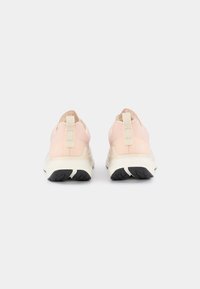 Scarpe da ginnastica rosa pallido con tacco alto, materiale testurizzato, linguetta sul retro e suola bianca con battistrada in gomma nera.