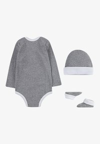 Grå långärmad bodysuit med vit kant, tillsammans med en grå hatt och grå babyskor med vita manschetter, allt i mjukt tyg.