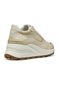 Zapatilla beige con cuero texturizado y paneles de malla, suela blanca gruesa y acentos dorados en el talón y el logo, con un diseño en la parte trasera.