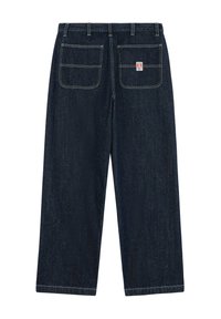 Pantalon en jean bleu foncé à coupe droite, avec deux poches plaquées à l’arrière, coutures visibles et petit logo rectangulaire sur la poche droite.
