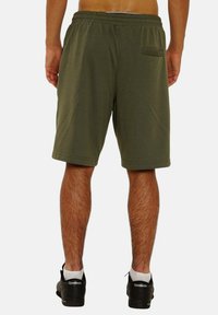 Grüne Sportshorts mit einem elastischen Bund, Seitentaschen und einer Gesäßtasche. Aus einem leichten Stoff gefertigt, reichen sie bis über das Knie.