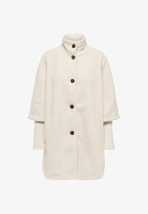 Abrigo de lana blanca con un cuello alto, mangas cortas, tres botones marrones y bolsillos laterales. Presenta una tela texturizada y suave.