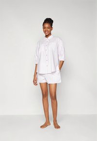 Hvitt pysjamasett med lyserosa vertikale striper. Kortermet skjorte med knapper og matchende shorts. Mykt stoff, avslappet passform.