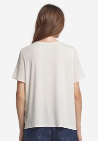 Vit t-shirt med kort ärm och rund halsringning, tillverkad av slät tyg. Har en avslappnad passform, rak nederkant och inga synliga dekorativa detaljer.