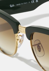 Ray-Ban prillid tumerohelise plastraami, kuldsete detailide, pruunide gradueeritud läätsede ja reguleeritavate nina padjanditega. Valmistatud Itaalias.