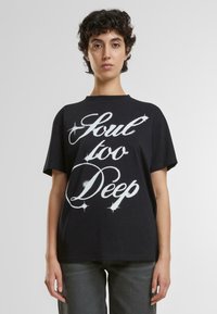 Camiseta de algodón negra de manga corta, con el texto en blanco, en negrita y estilizado "Soul too Deep" en el frontal. Cuello clásico tipo crew.