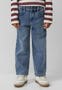 Lichtblauwe denim jeans met een ontspannen pasvorm, iets vervaagde textuur en vijf zakken. Draagt een rood-wit gestreept lange mouwen shirt.