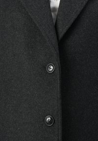 Dark gray wool coat featuring a structured lapel, three buttons, and a soft, textured finish. Buttons are black with a logo detail.