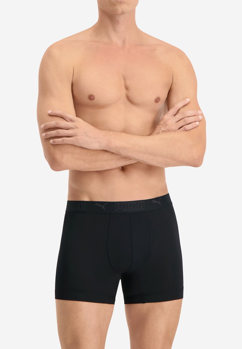 Schwarze Boxerbriefs aus glattem Material mit einer engen Passform. Sie haben einen kontrastierenden elastischen Bund mit dem Markennamen "PUMA" in Schwarz.
