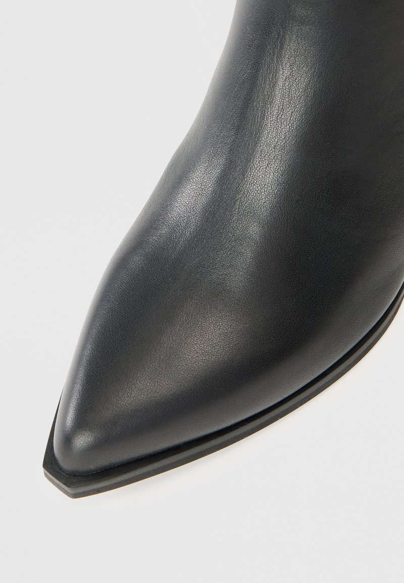 Schwarze Leder-Ankle-Boots mit spitzer Zehenform, glatter Textur und dünner Sohle. Minimalistisches Design ohne sichtbare Beschläge oder Akzente.