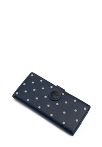 Navy blue wallet made of synthetic leather, featuring white polka dots, a snap closure, and a round black accent with logo detail.
