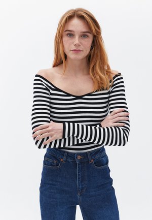 Zwart-wit gestreepte lange mouwen top met een off-the-shoulder halslijn, gecombineerd met hoogwaisted blauwe denimjeans. Glad, ribbelachtig textuur.