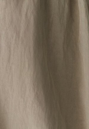 Bežinė medvilnės audinys su įstrižiniu raštu ir subtiliomis vertikaliomis raukšlėmis, apšviestas švelnia šviesa.