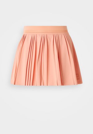 Perzikkleurige geplooide rok met een brede elastische tailleband en een zachte textuur. Heeft een eenvoudig logo detail aan de onderzijde rechts.