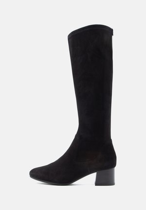 Térd magasított fekete velúr csizmák lekerekített orral és masszív blokk fallal. Sim পাতólón p Surface készíté leicht e minimalista részletekkel és egyszerű siluettal.